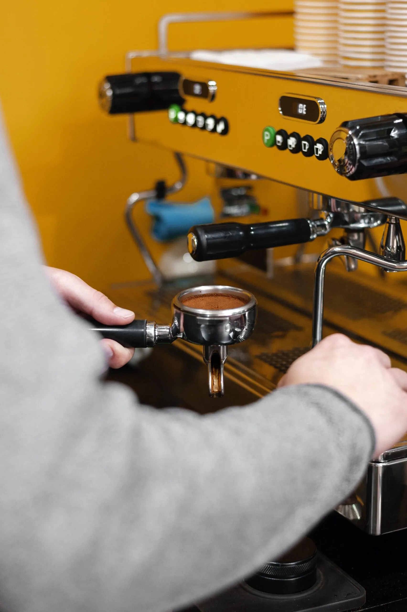 Barista purging the group head while cleaning a professional coffee machine